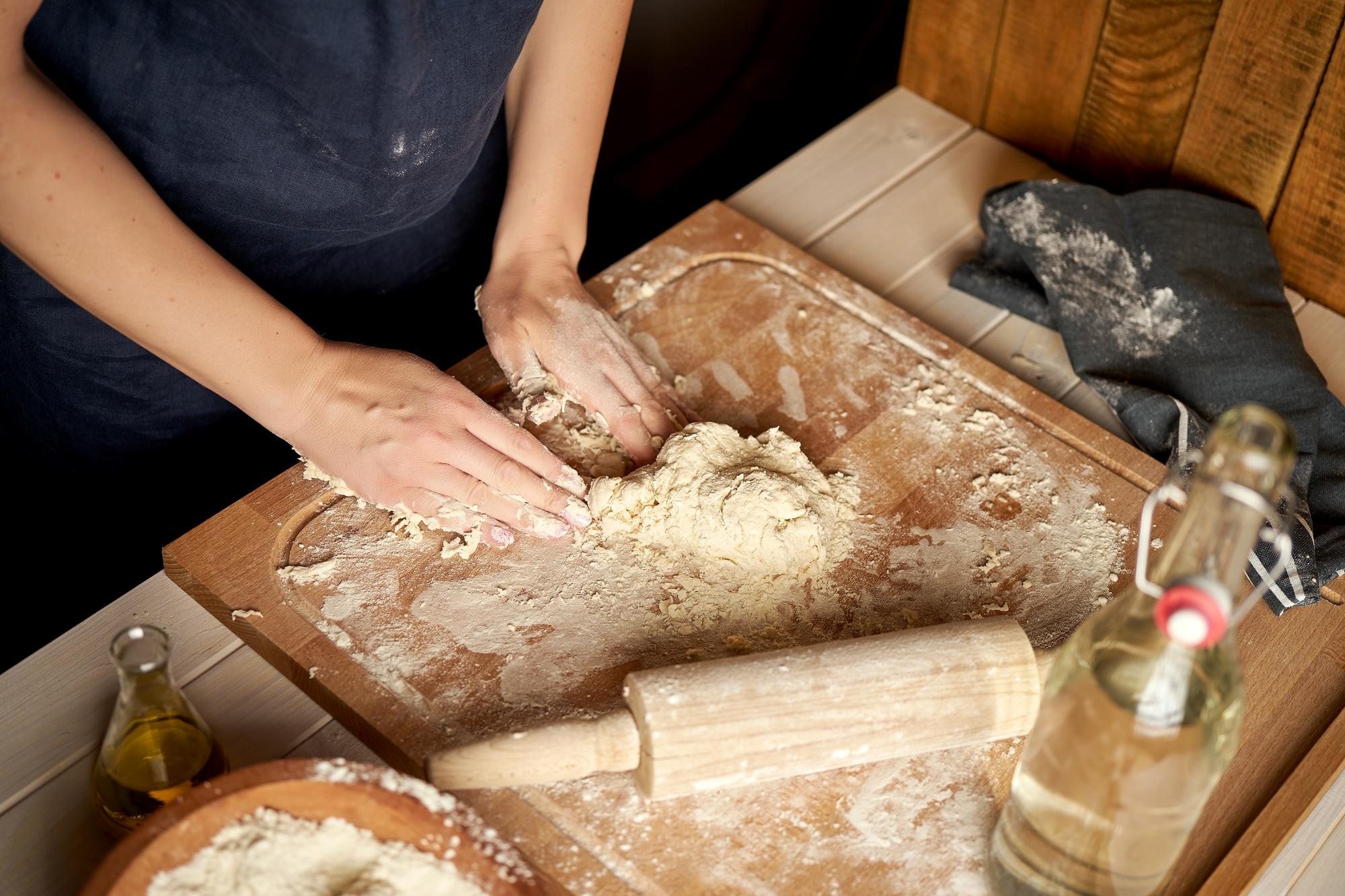 Close-up of hands kneading dough in workshop
